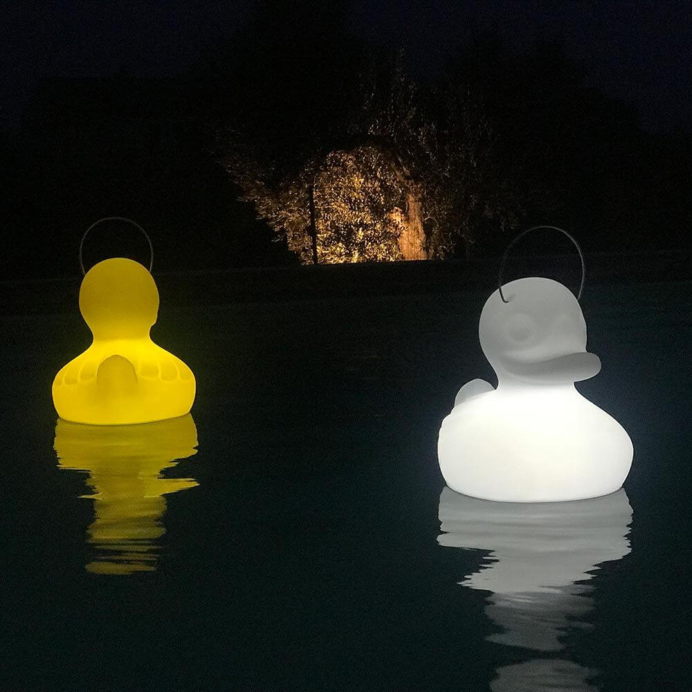 Schwimmfähige Akku-LED-Leuchte Duck-Duck S Gelb und weiße Ente im Wasser bei Nacht.
