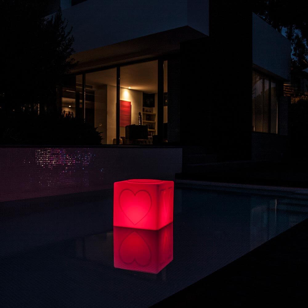 Schwimmfähiger Akku-LED-Lichtwürfel in Herzform leuchtet rot am Pool bei Nacht.