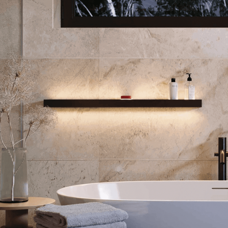 Elegante Badezimmerregal mit sanfter Beleuchtung, Shampoo und Handtuch neben dekorativen Pflanzen.