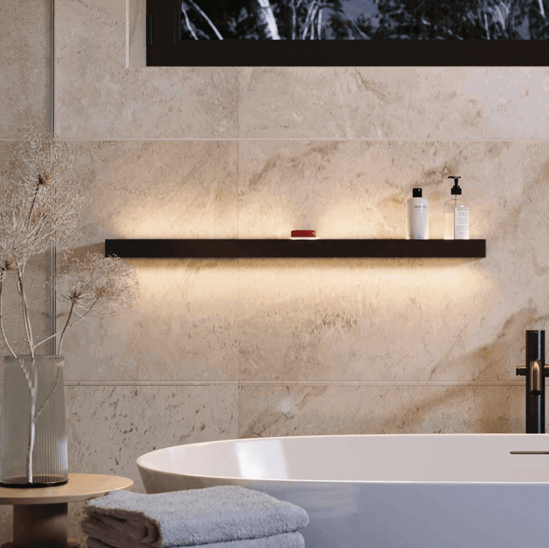 Elegante Badezimmerregal mit sanfter Beleuchtung, Shampoo und Handtuch neben dekorativen Pflanzen.