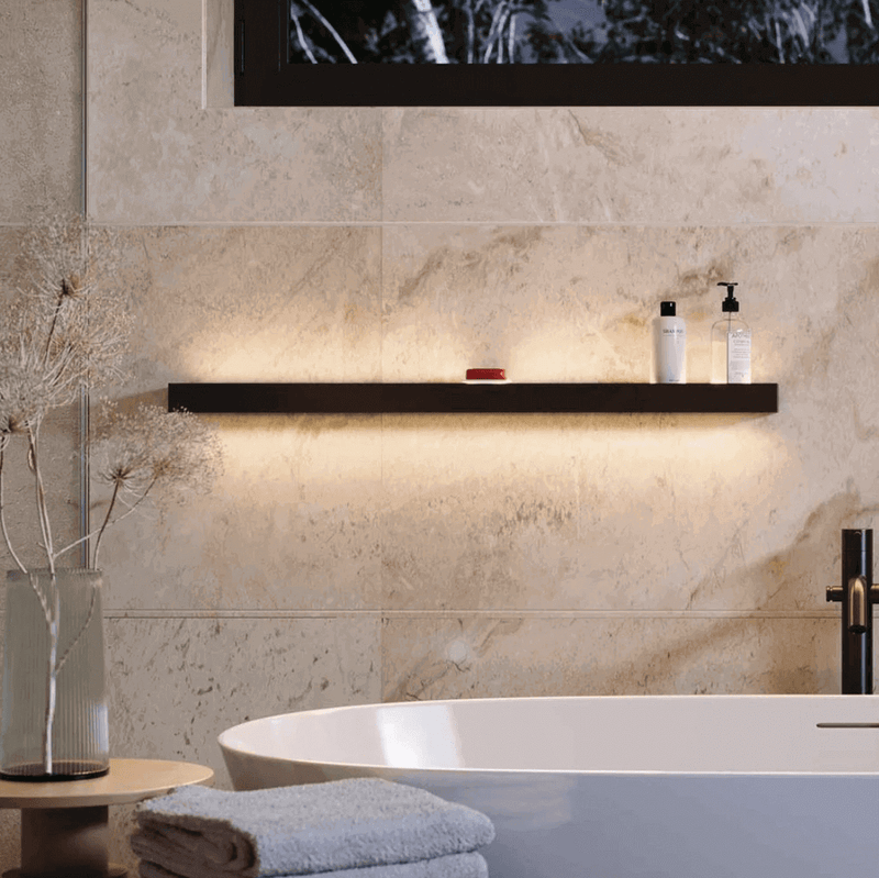 Elegante Badezimmerregal mit sanfter Beleuchtung, Shampoo und Handtuch neben dekorativen Pflanzen.