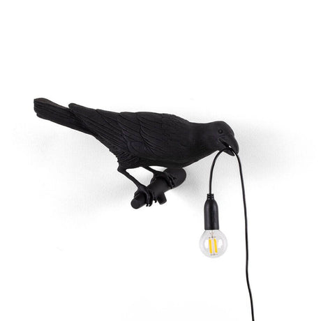 Seletti Bird Wandleuchte nach rechts Schauend mit schwarzem Raben und Glühbirne.