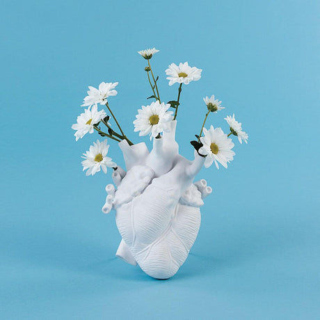 Applique murale et vase Seletti Heart avec des fleurs blanches sur fond bleu.