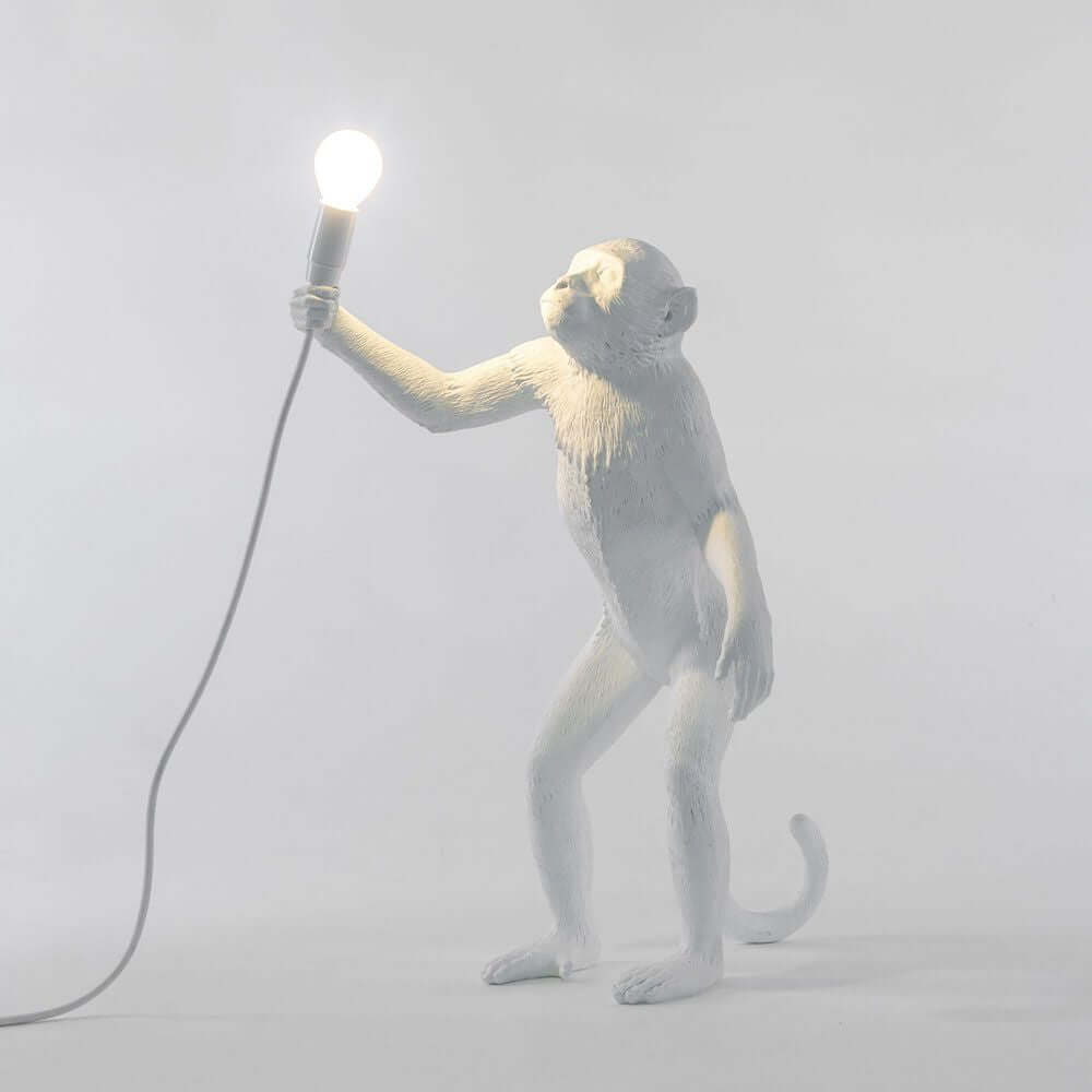 Seletti Monkey Außen-Tischleuchte: eleganter Affe hält leuchtende Glühbirne, perfekte Kombination aus Kunst und Design.