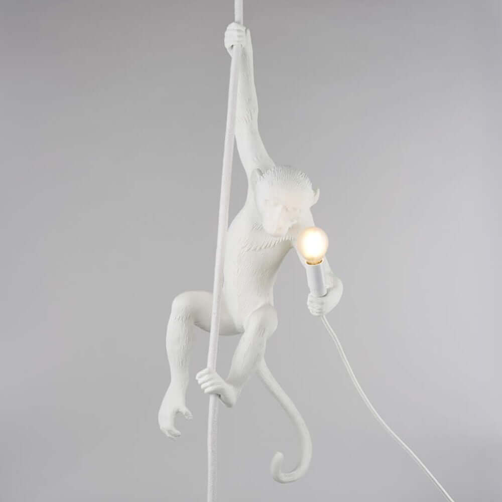 Seletti Monkey Ceiling Pendelleuchte Weiß mit Affe, der an Seil hängt und Lampe hält.