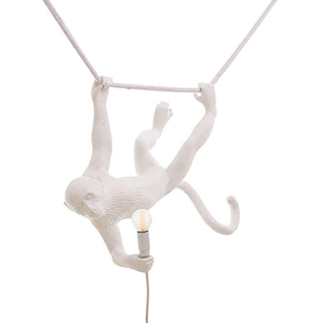 Seletti Monkey Swing Pendelleuchte Weiß mit einem schwingenden weißen Affen, der eine Lampe hält.