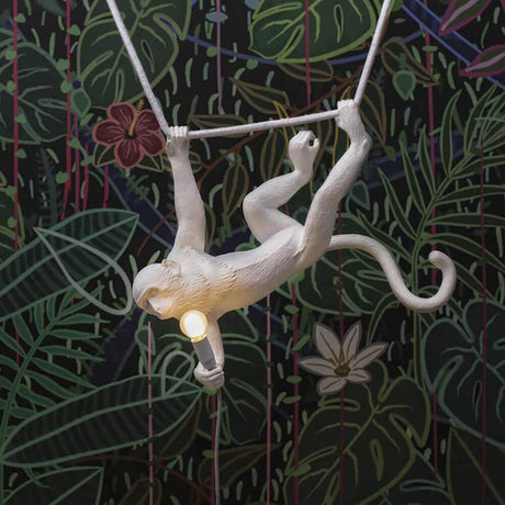 Seletti Monkey Swing Pendelleuchte Weiß hängt an einer Schnur in einem Dschungel-Muster Hintergrund.