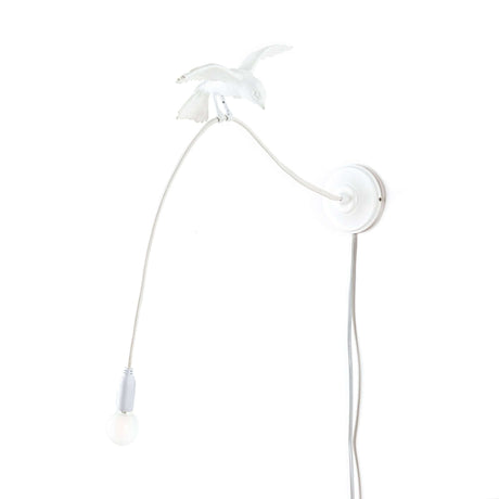 Applique murale Seletti Sparrow Cruising LED - applique murale blanche en forme de moineau en résine et acier, l’oiseau tient le câble et l’ampoule LED, designer Marcantonio