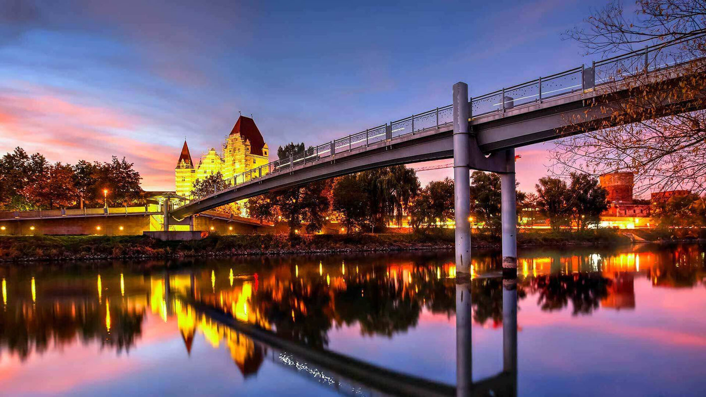 Die romantische Brücke bei Sonnenuntergang mit reflektierenden Lichtern im Fluss.