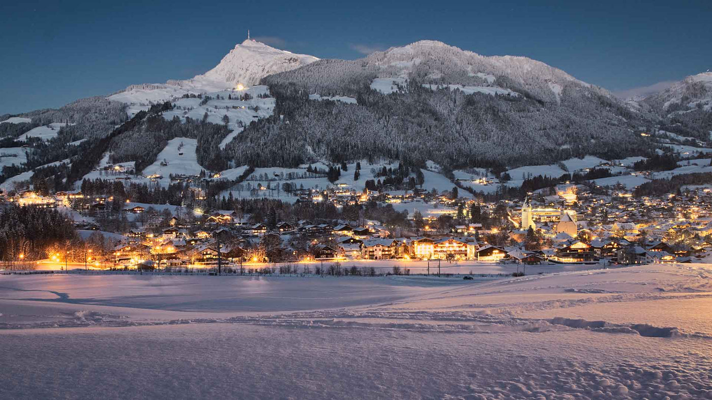 Glocknerblick in der Nacht zeigt das verschneite Dorf in der Winterlandschaft mit beleuchteten Gebäuden.