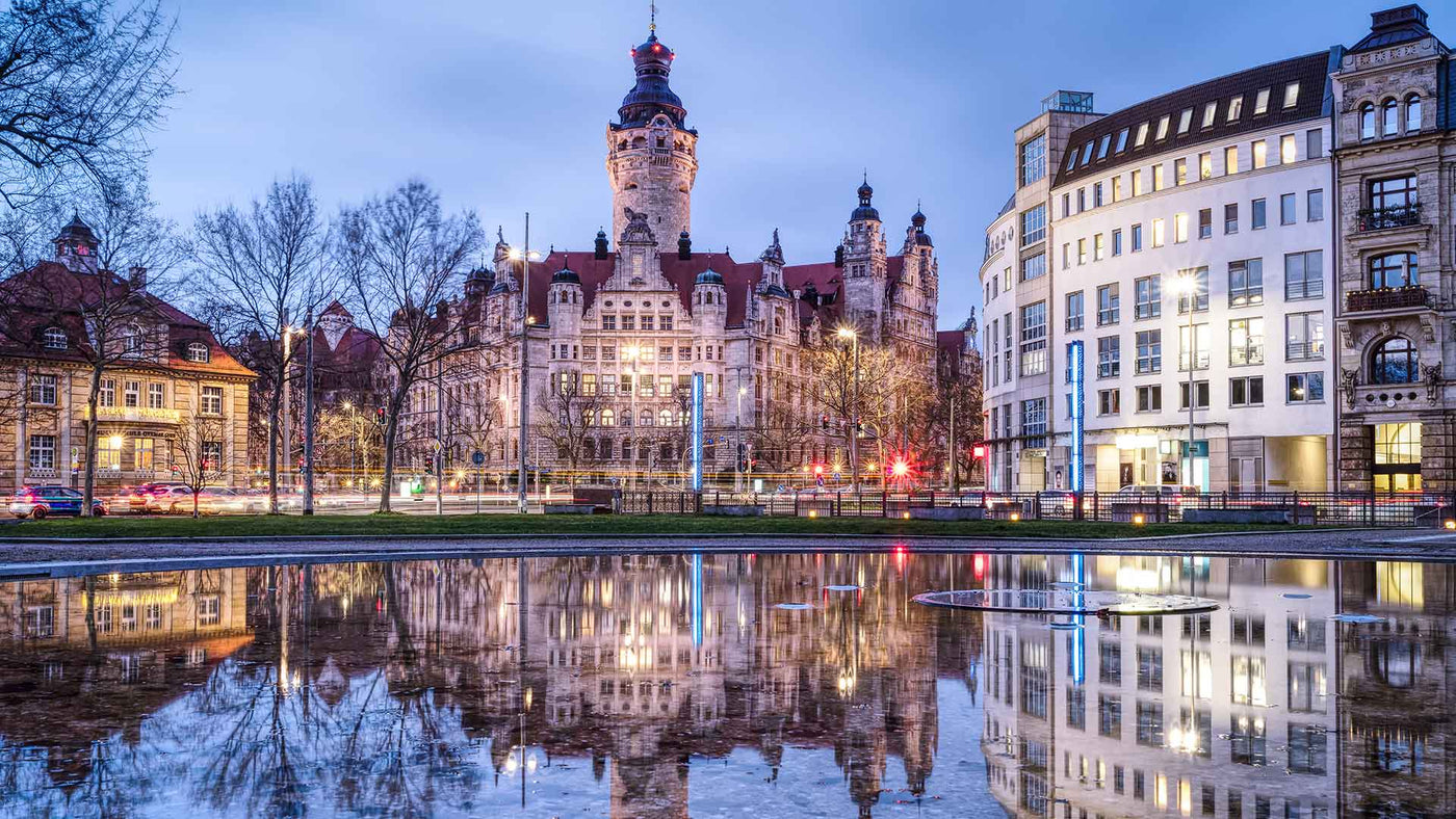 Schöne Stadtszene in Leipzig mit reflektierenden Gebäuden im Wasser bei Dämmerung.