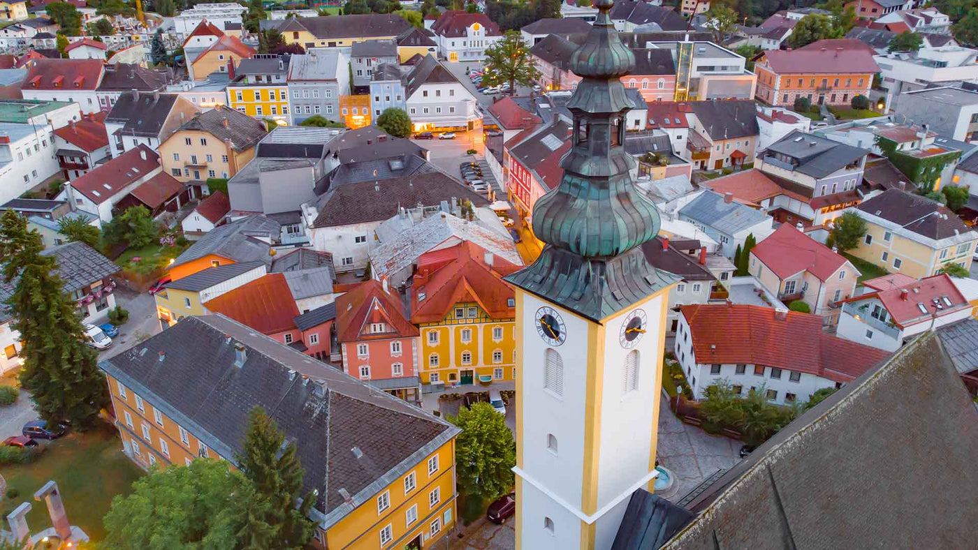 Panoramablick auf die Stadt, mit bunten Häusern und einem beeindruckenden Kirchturm bei Sonnenuntergang.