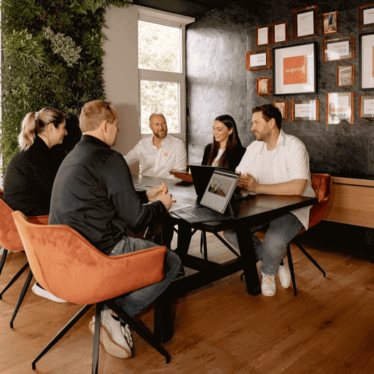 Besprechungstisch mit fünf Personen, die an einem kreativen Teammeeting teilnehmen.