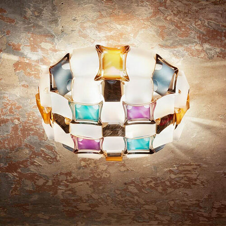 Slamp Decken- & Wandlampe Mida in schillernden Farben auf dekorativem Hintergrund.