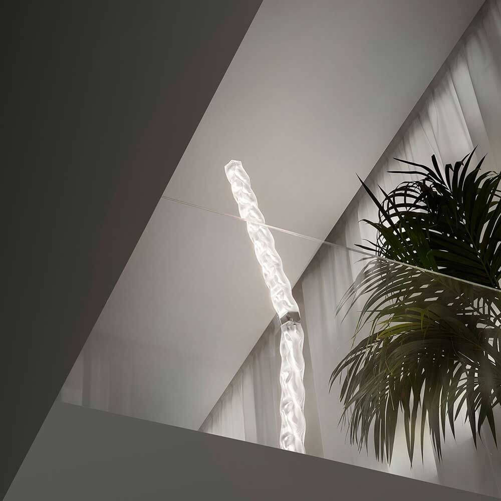 Slamp Hugo Stehleuchte 207cm aus Lentiflex-Kunststoff in einem modernen Raum mit Pflanze.