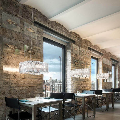 Innenansicht eines modernen Restaurants mit Slamp LED Hängelampe Accordeon Ø 57cm über den Tafeln.