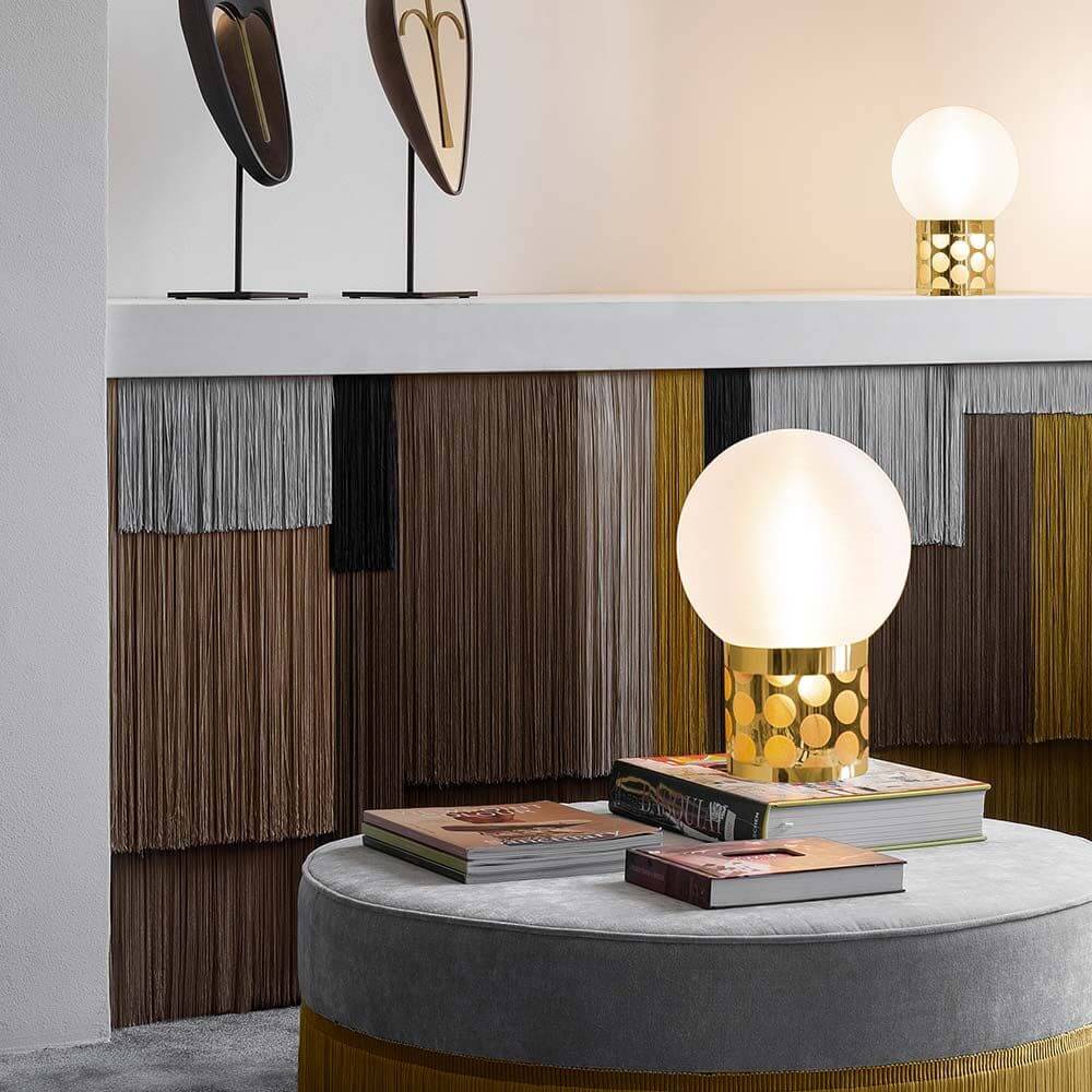 Slamp Tischlampe Atmosfera auf einem Tisch mit stilvollen Büchern und dekorativen Elementen.