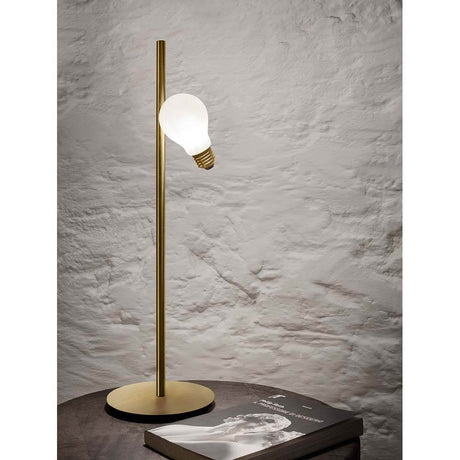 Slamp Tischlampe Idea mit Glühbirne LED Messing-matt auf einem Tisch mit Magazin.