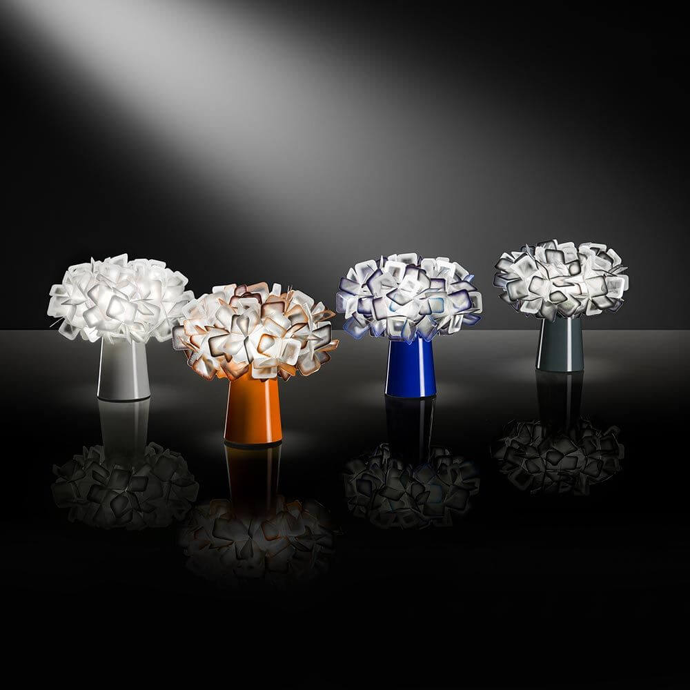 Slamp Tischleuchte Clizia Orange und weitere Farben auf einem eleganten Tisch.