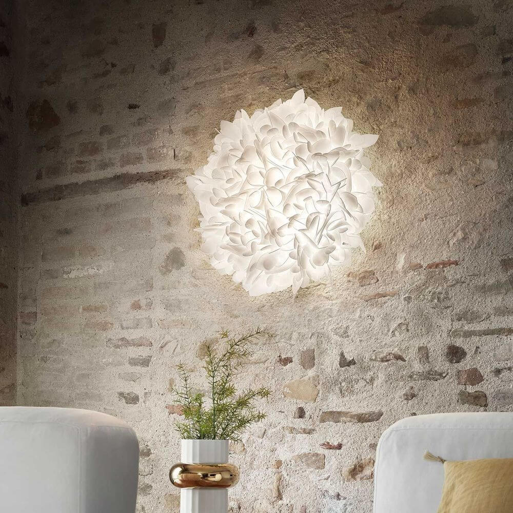 Slamp Wand- & Deckenlampe Veli Foliage an einer rustikalen Wand mit sanfter Beleuchtung.