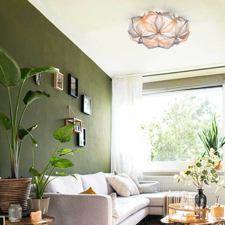 Slamp wall and ceiling light La Vie effect lamp in the living room above a sofa and plants.
