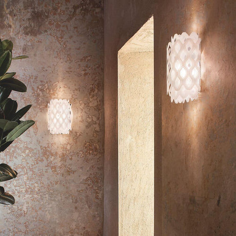 Slamp Wandlampe Charlotte Applique Weiß an einer Wand, mit wabenförmiger Struktur, die warmes Licht erzeugt.