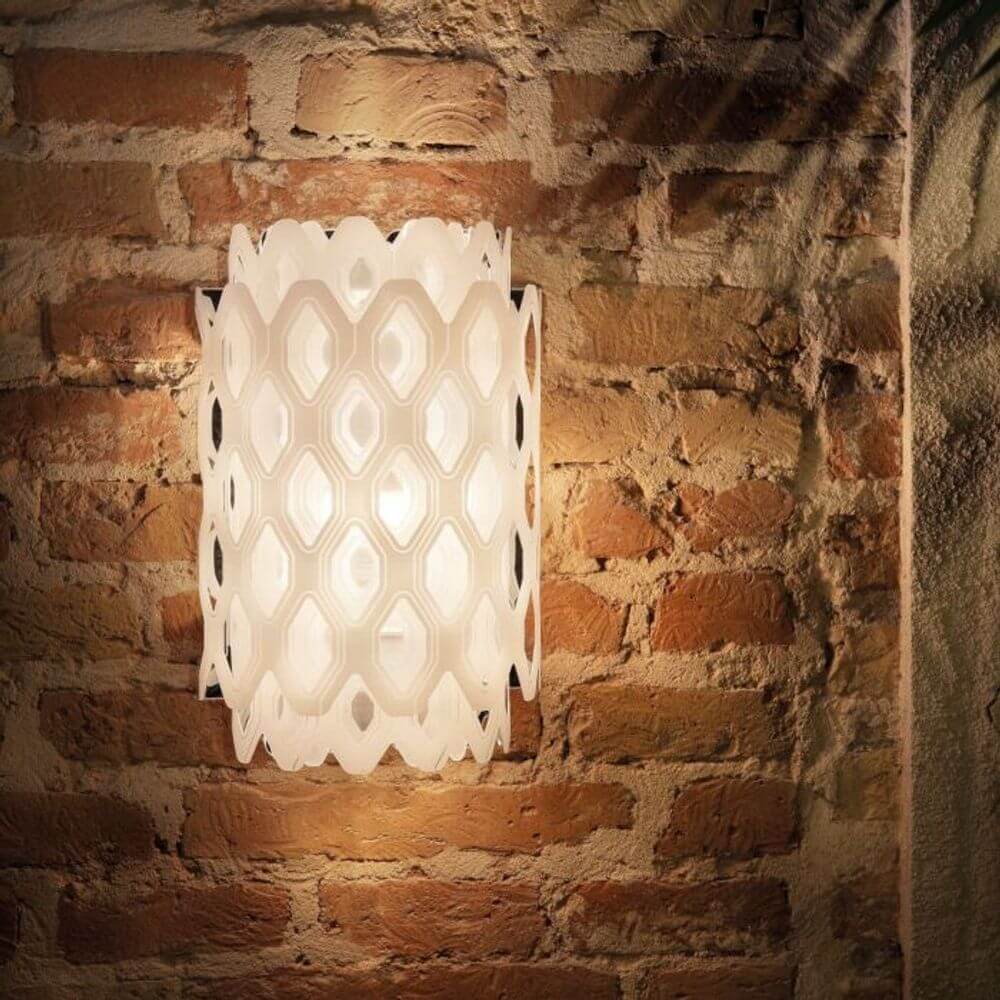 Slamp Wandlampe Charlotte Applique Weiß an einer Ziegelwand, mit wabenförmiger Struktur für weiches Lichtspiel.