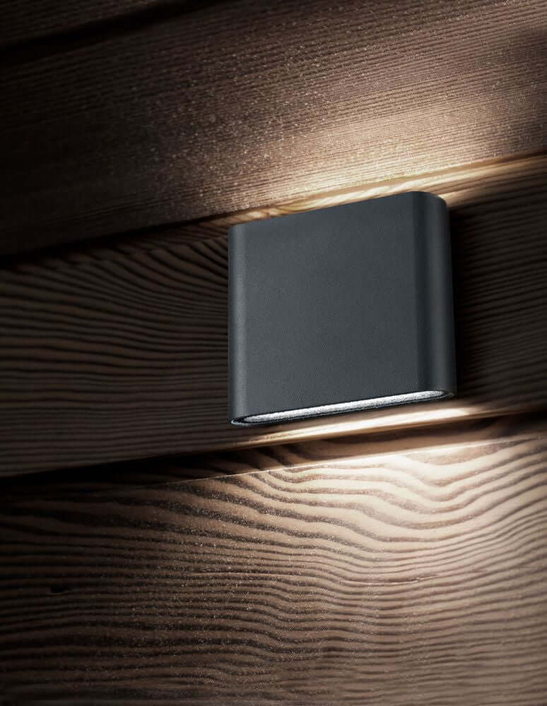 Soho LED Außenwandleuchte Qudadratisch Up & Down 3000K IP54 an Holzfassade montiert, warmweißes Licht abstrahlend.