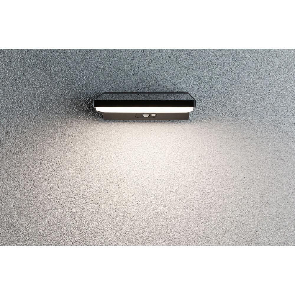Solar LED Außenwandlampe Ronas Bewegungsmelder Grau an einer Wand mit warmweißem Licht.