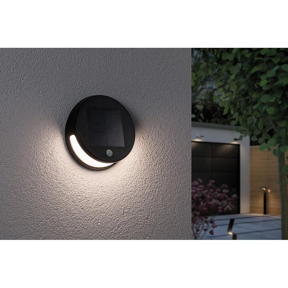 Solar LED Außenwandleuchte Helena Bewegungssensor Anthrazit an einer Wand installiert, mit aktivem Licht.