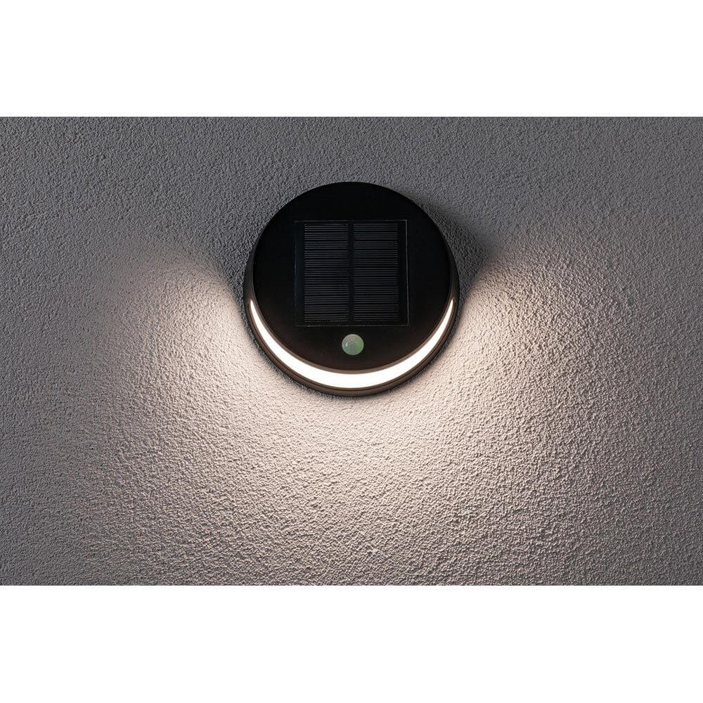 Solar LED Außenwandleuchte Helena Bewegungssensor Anthrazit an einer Wand montiert, mit solarem Aufladepanel und Bewegungsmelder.