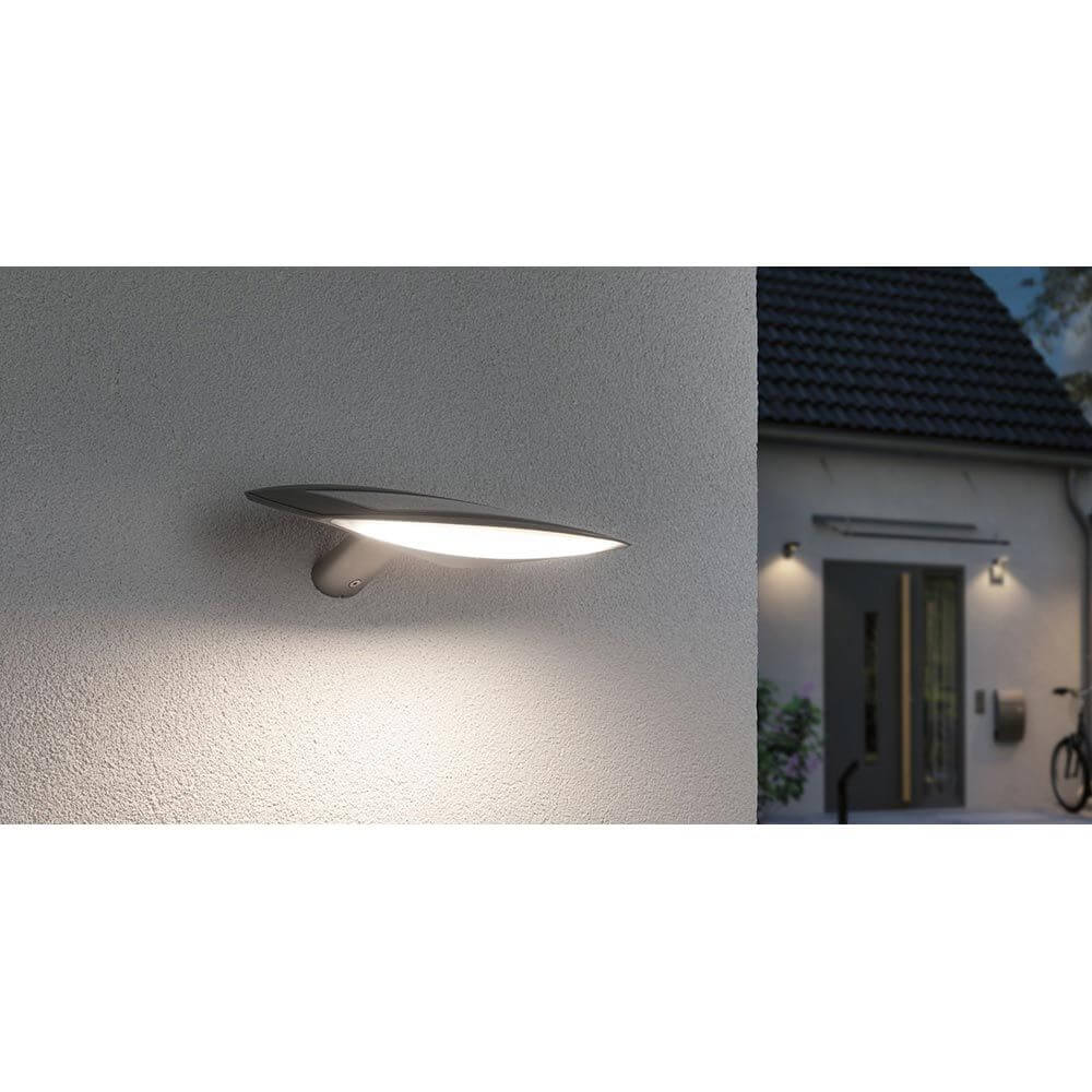 Solar LED Außenwandleuchte Kiran Bewegungssensor Weiß an Außenwand montiert, beleuchtet Bereich.