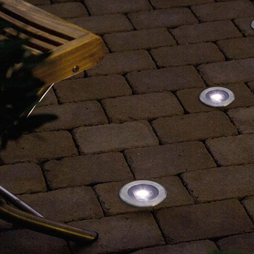 Solar LED Bodenspot aus Edelstahl mit klarem Glas auf einem gepflasterten Weg im Garten