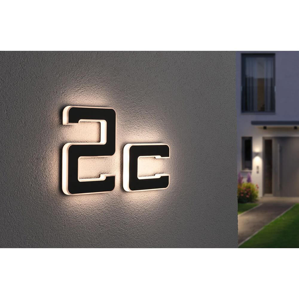 Solar LED Hausnummernleuchte Buchstabe C Schwarz an der Wand montiert, in warmweißem Licht beleuchtet.