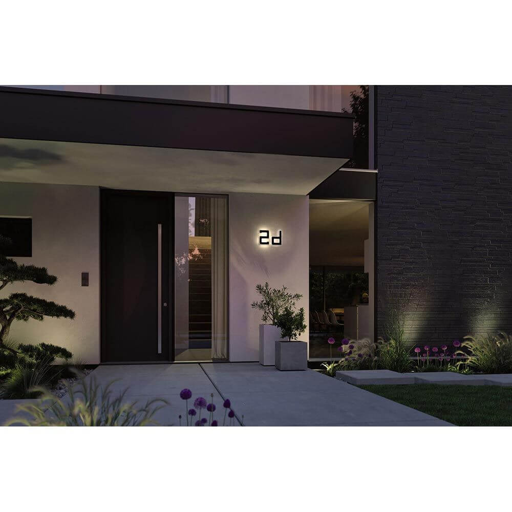 Solar LED Hausnummernleuchte Buchstabe D in Schwarz, beleuchtet an einem modernen Eingang. Warmweißes Licht, 3000K.