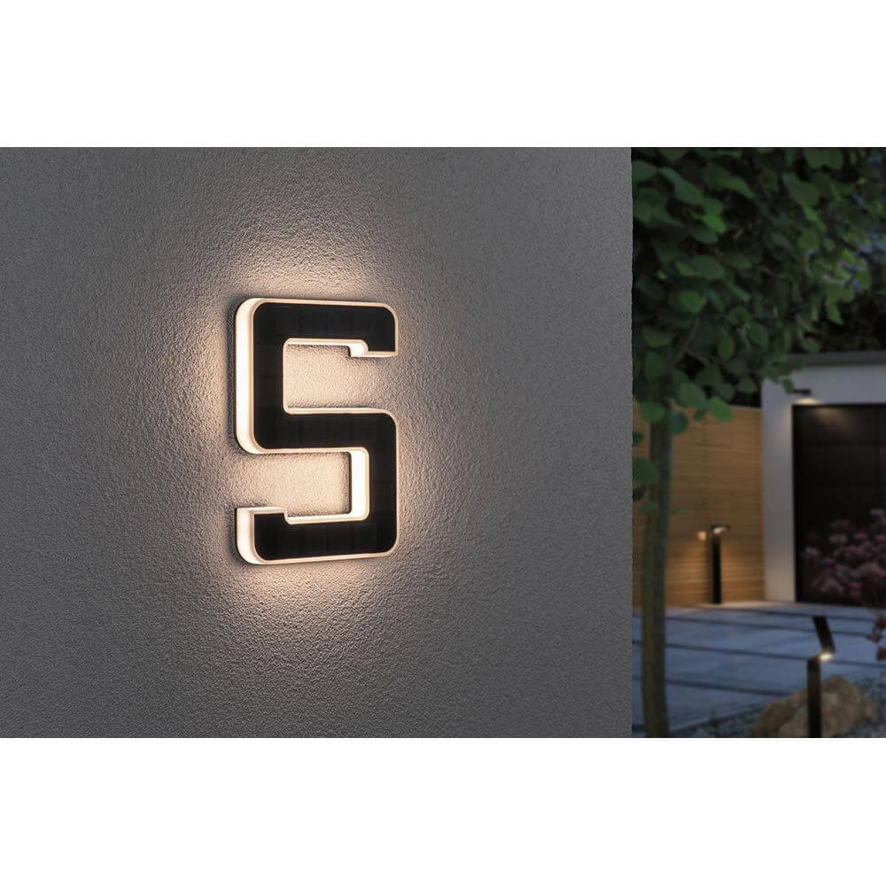 Solar LED Hausnummernleuchte Nummer 5 an einer Wand, bei Nacht sichtbar, warmweißes Licht.