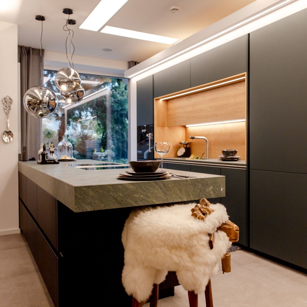 Moderne Küche mit eleganter Kochinsel, Schwarz und Holz, und stilvollen Hängelampen im Hintergrund.
