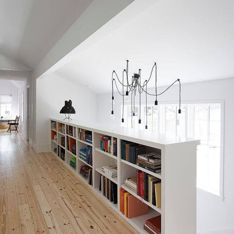 Spid pendellampe med 5 lyskilder i edderkoppform, svart, over en moderne bokhylle i et lyst rom
