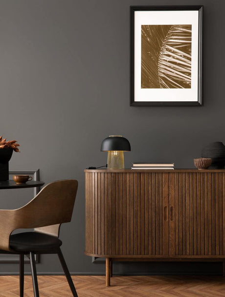 Sqube Tischleuchte Schwarz, Gold auf Holzkommode, elegante Tischlampe mit mattschwarzem Schirm und goldfarbenem Gitter