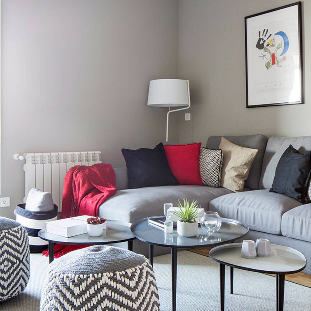 Stehlampe BERNI Weiß in modernem Wohnzimmer mit grauem Sofa und dekorativen Kissen.