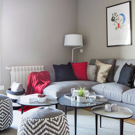 Stehlampe BERNI Weiß in modernem Wohnzimmer mit grauem Sofa und dekorativen Kissen.