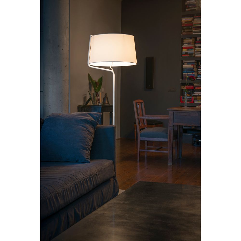 Stehlampe BERNI Weiß steht neben einem blauen Sofa in einem gemütlichen Wohnzimmer mit Bücherregal.