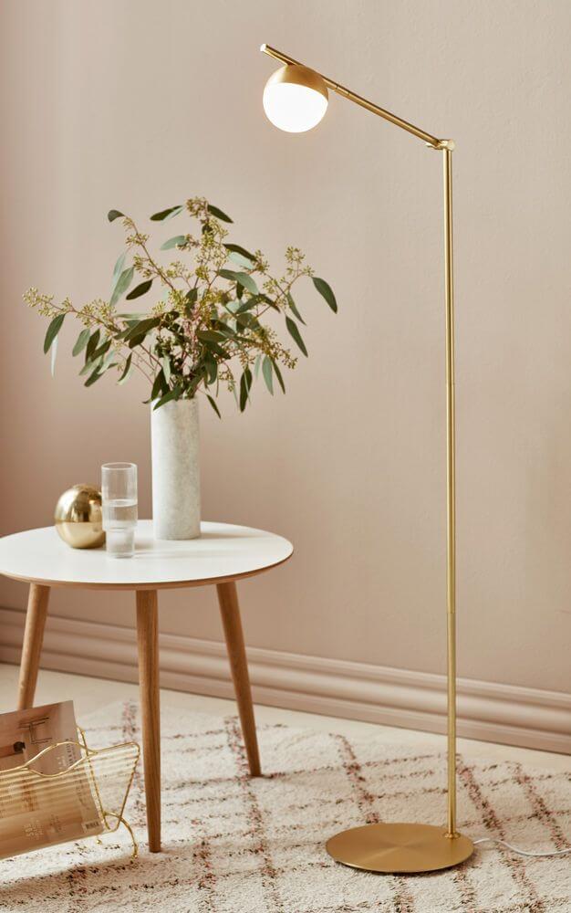 Stehlampe Contina in elegantem Design mit einer kugelförmigen Glaskuppel und goldfarbenem Gestell.