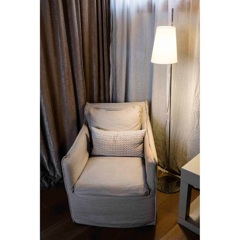 Stehlampe LUPE Chrom, Weiß neben einem beigen Sessel in einem stilvoll eingerichteten Raum.
