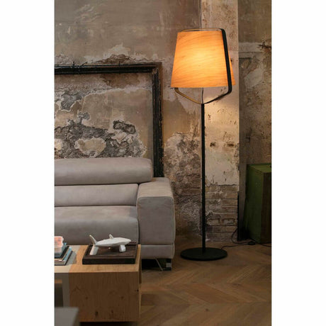 Stehlampe STOOD Schwarz, Braun in modernem Wohnraum mit grauem Sofa und rustikalem Hintergrund.