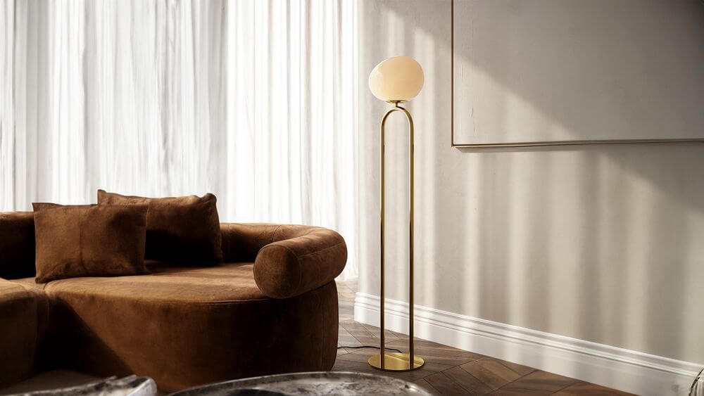 Stehlampe Shapes mit opalgläsernem Schirm und elegantem Messingfuß in modernem Wohnambiente.