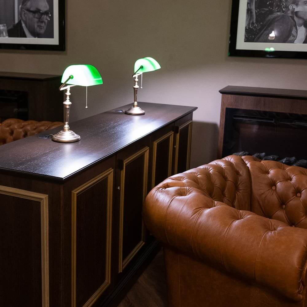 Vintage Tischleuchte Ancilla mit grünem Glasschirm auf einem modernen Tisch im eleganten Ambiente.