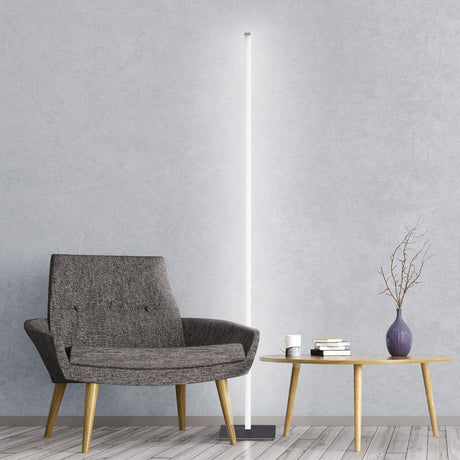 Candeeiro de pé duradouro Sting Dim2warm LED ao lado de uma poltrona e mesa modernas num espaço elegante.