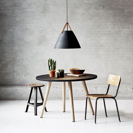 Suspension Strap 48 Ø 48 cm avec 2 sangles en cuir noir au-dessus d’une table moderne avec des chaises.