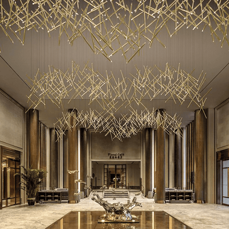 Lodes A-Tube Nano Duo LED Pendellampe in eleganter Lobby mit goldenen Leuchten dezentral aufgehängt.